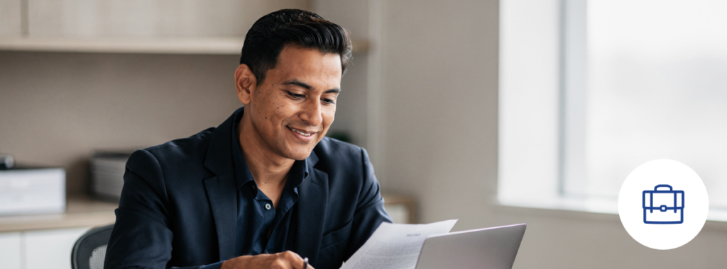 Latin small business owner reviewing documents in modern office with laptop
