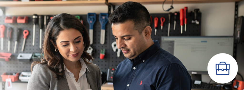 Latin business owner reviewing inventory with colleague in modern office, business personal property insurance